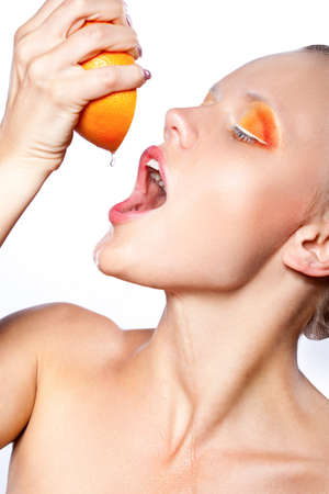 beautiful woman with creative orange makeup  squeezing  grapefruit juiceの写真素材