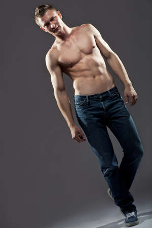 Sexy guy shirtless man with a muscular body posing in jeans, full lenght portraitの写真素材