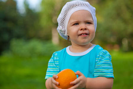 cute baby girl wearing blue dress  holding orangeの写真素材