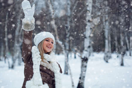 woman waving in winter park during snowfallの写真素材