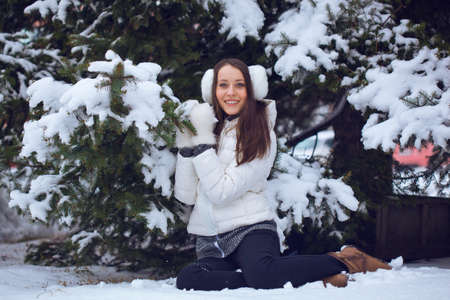 brunette woman sitting  in winter park under fur tree