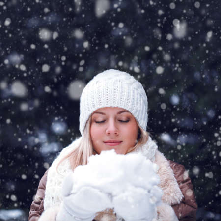 happy blonde woman with closed eyes holding snowの写真素材