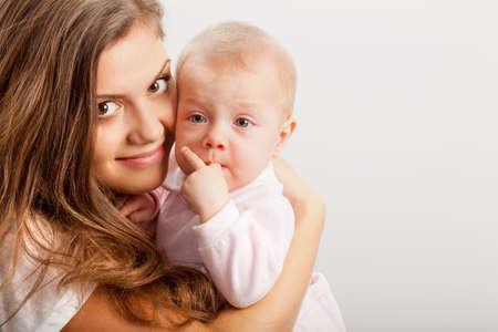 happy young mother  embracing her baby girl over whiteの写真素材