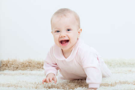 happy little baby girl creeping on the carpet at homeの写真素材