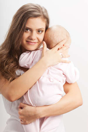 happy young mother  holding her baby girl on hands over whiteの写真素材