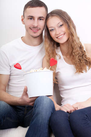 happy smiling  young couple sitting with popcorn, valentines themeの写真素材