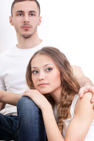 sitiing young couple closeup portrait over whiteの写真素材