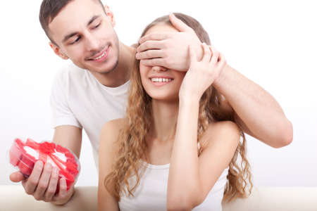 young man gives his girlfriend a heart-shaped box, he covered her eyes with  handの写真素材