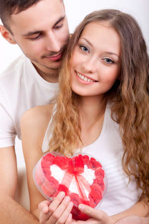 young man gives his girlfriend a heart-shaped boxの写真素材