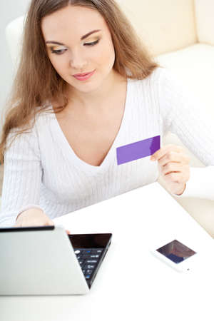 woman working with laptop and holding blank bank cardの写真素材