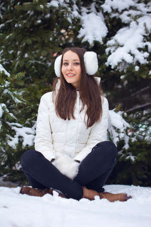 brunette woman sitting  in winter park under fur treeの写真素材