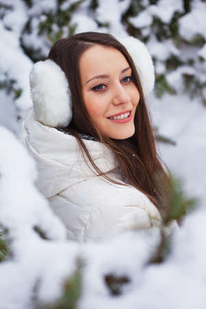 brunette woman sitting  in winter park under fur treeの写真素材