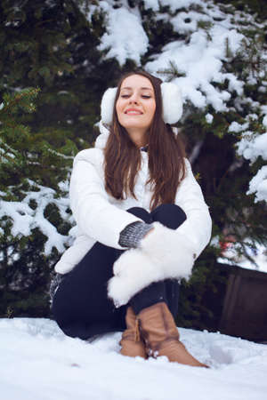 brunette woman sitting  in winter park under fur treeの写真素材