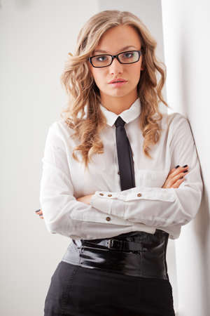 closeup seriously blonde businesswoman portrait wearing eyeglasses standing near wallの写真素材