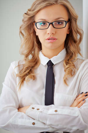 closeup seriously blonde businesswoman portrait wearing eyeglasses standing near wallの写真素材