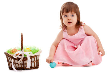 little girl playing with eater eggs near basket over white backgroundの写真素材