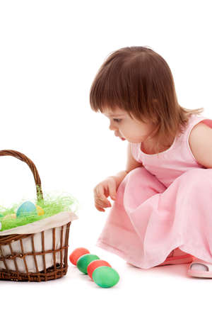little girl playing with eater eggs near basket over white backgroundの写真素材