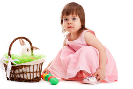 little girl playing with eater eggs near basket over white backgroundの写真素材
