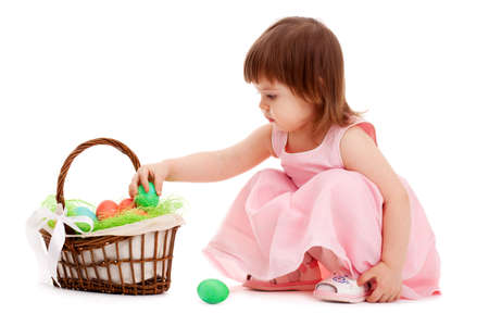 little girl playing with eater eggs near basket over white backgroundの写真素材