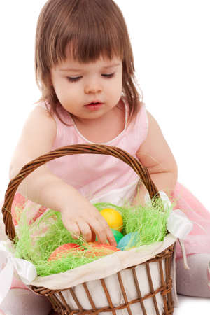 little girl playing with eater eggs near basket over white backgroundの写真素材