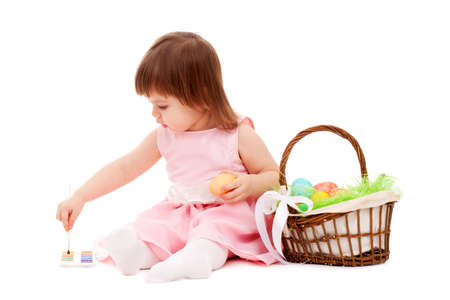 isolated little girl painting easter eggs over white backgroundの写真素材