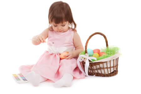 little girl painting easter eggs over white backgroundの写真素材