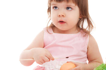 little girl painting easter eggs over white backgroundの写真素材