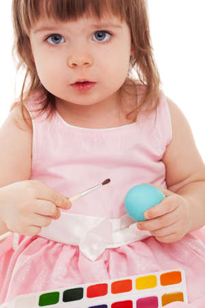 little girl painting blue easter egg over white backgroundの写真素材