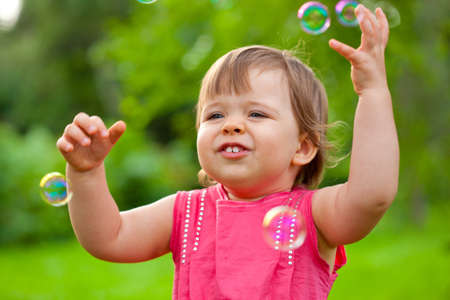 cute little girl at park with flying bubblesの写真素材