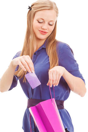 smiling blond woman put in card into bag over white backroundの写真素材