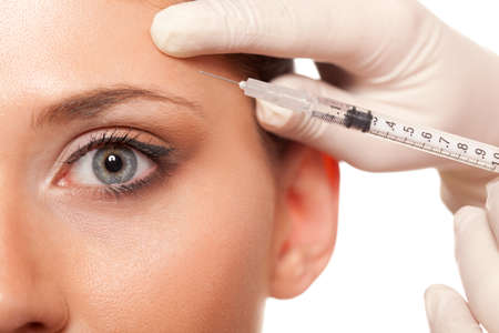 closeup beautiful woman eye, syringe injection beauty conceptの写真素材