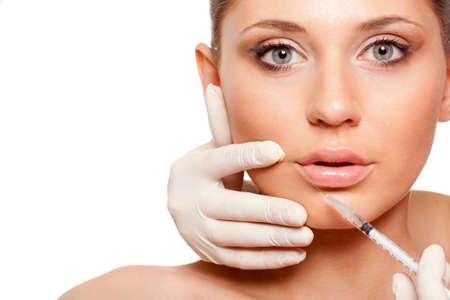 closeup beautiful woman face, syringe injection into lips, space for textの写真素材