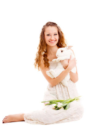 happy woman sitting on the floor with tulips and a rabbit, isolated over whiteの写真素材