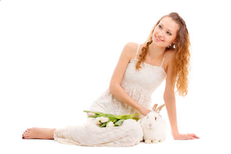 happy woman sitting on the floor with tulips and a rabbit, isoalted over whiteの写真素材