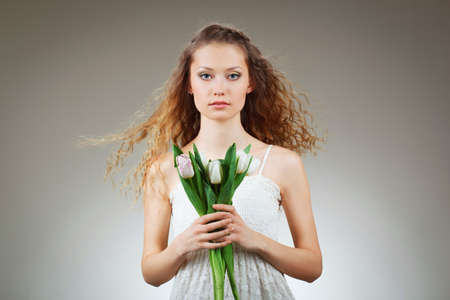 girl with curly hair holding a bucket of white tulipsの写真素材