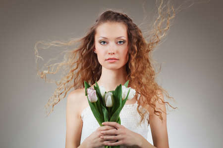 girl with curly hair holding a bucket of white tulipsの写真素材
