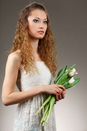 girl with curly hair holding a bucket of white tulipsの写真素材