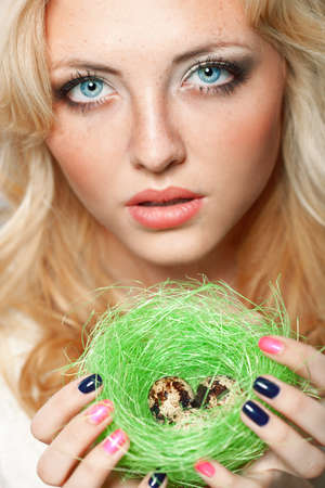 portrait of woman holding  green nest with quail eggsの写真素材