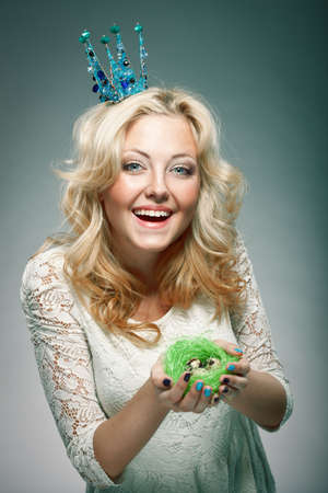 emotional portrait of woman wearing  blue princess crown and holding nest with quail eggsの写真素材
