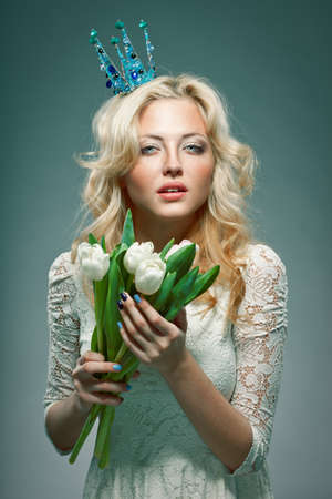 blonde girl wearing princess crown holding white tulipsの写真素材