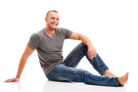 smiling strong casually dressed man over white background sitting on the floorの写真素材