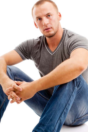 smiling strong casually dressed man over white background sitting on the floorの写真素材