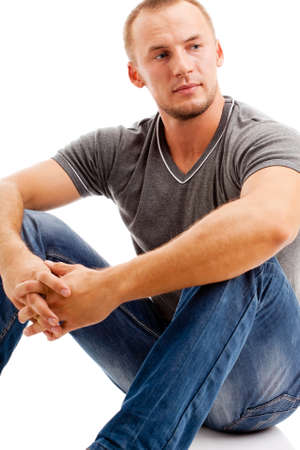 smiling strong casually dressed man over white background sitting on the floorの写真素材