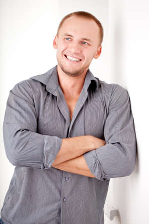 smiling strong casually dressed man near white wallの写真素材