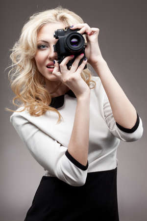 closeup beautiful blonde girl shooting with retro cameraの写真素材