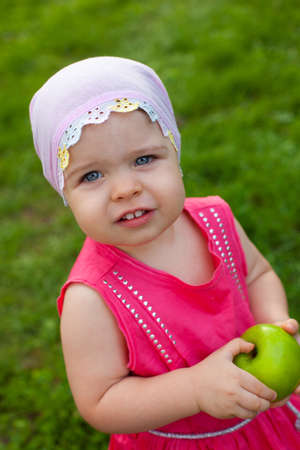 cute little girl walking in the park with green apple, top point of viewの写真素材
