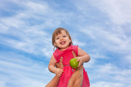 happy little baby girl over blue skies in father handsの写真素材