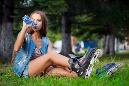 girl sitting on the grass and drinking water from bottleの写真素材