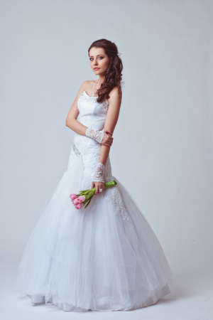 beautiful bride holding bouquet studio full length portrait, toned imageの写真素材