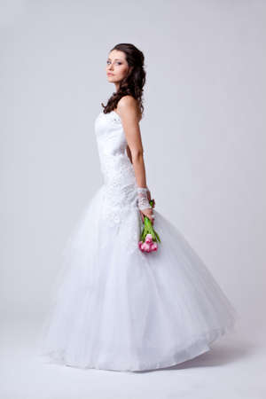 beautiful bride holding bouquet studio full length portrait and turned sidewaysの写真素材